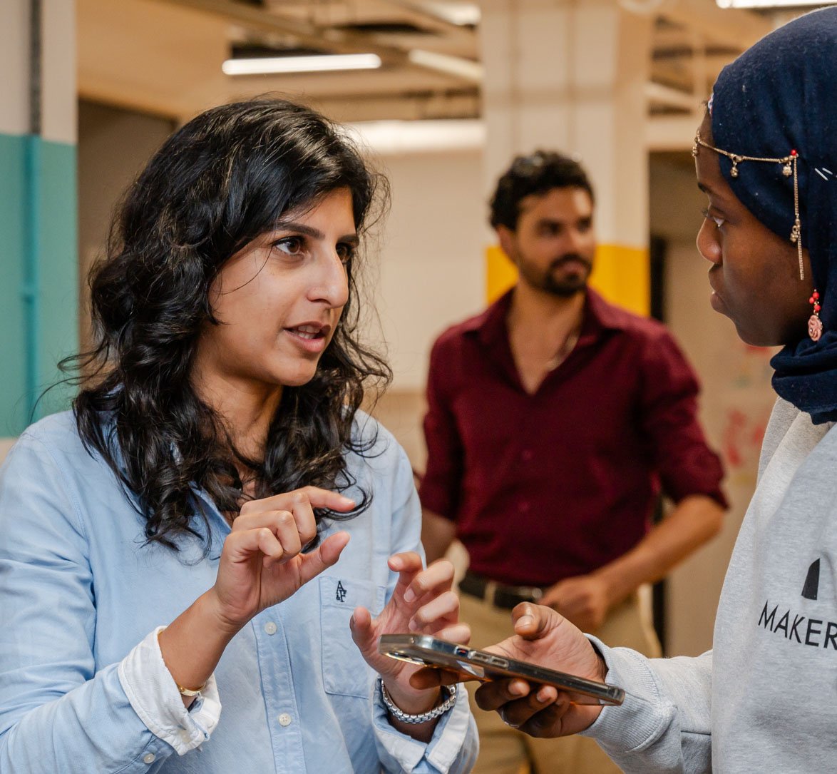 Makers tutor meeting with femal student as a man passes by behind