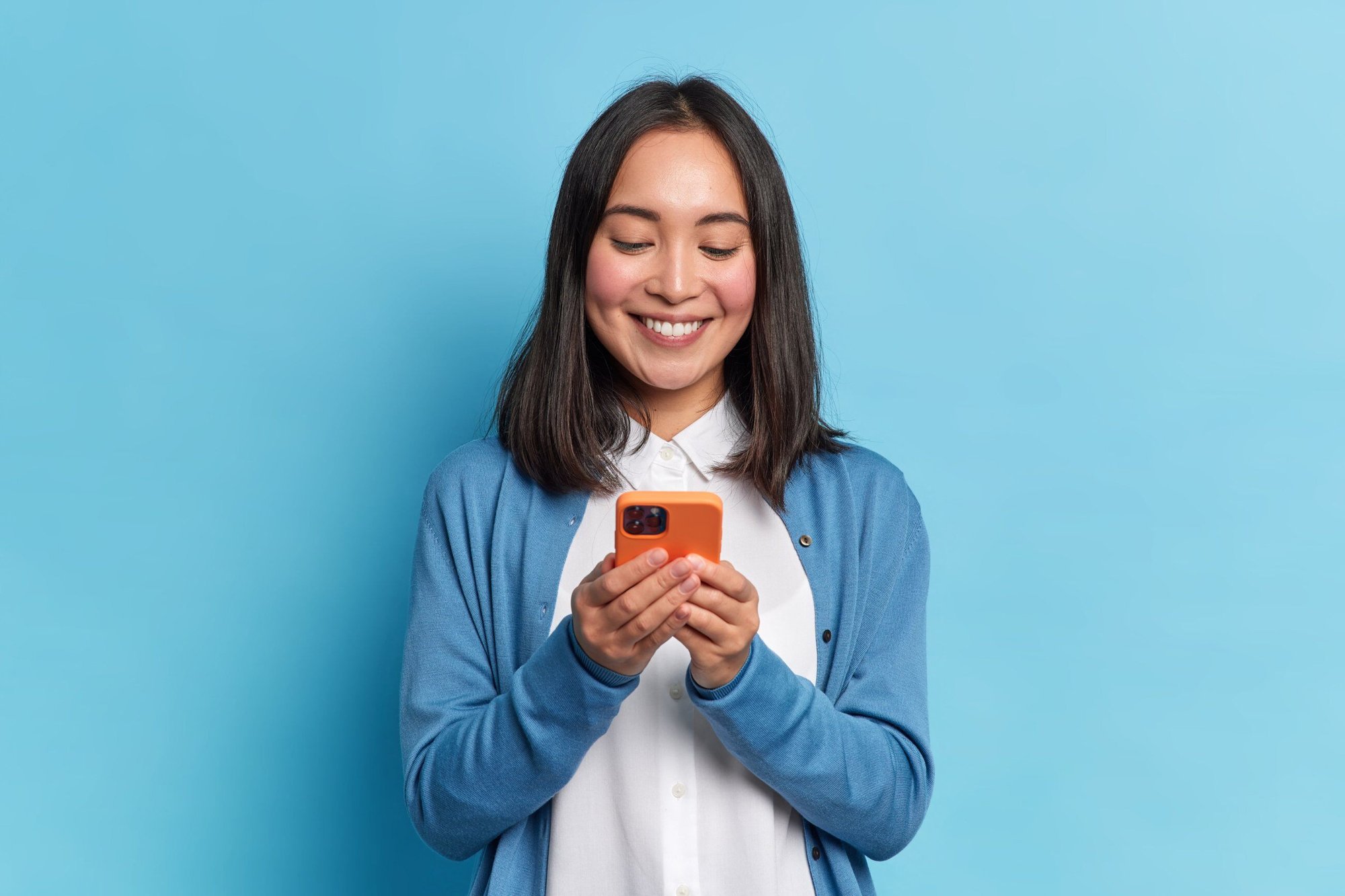 Woman smiling with phone on blue background