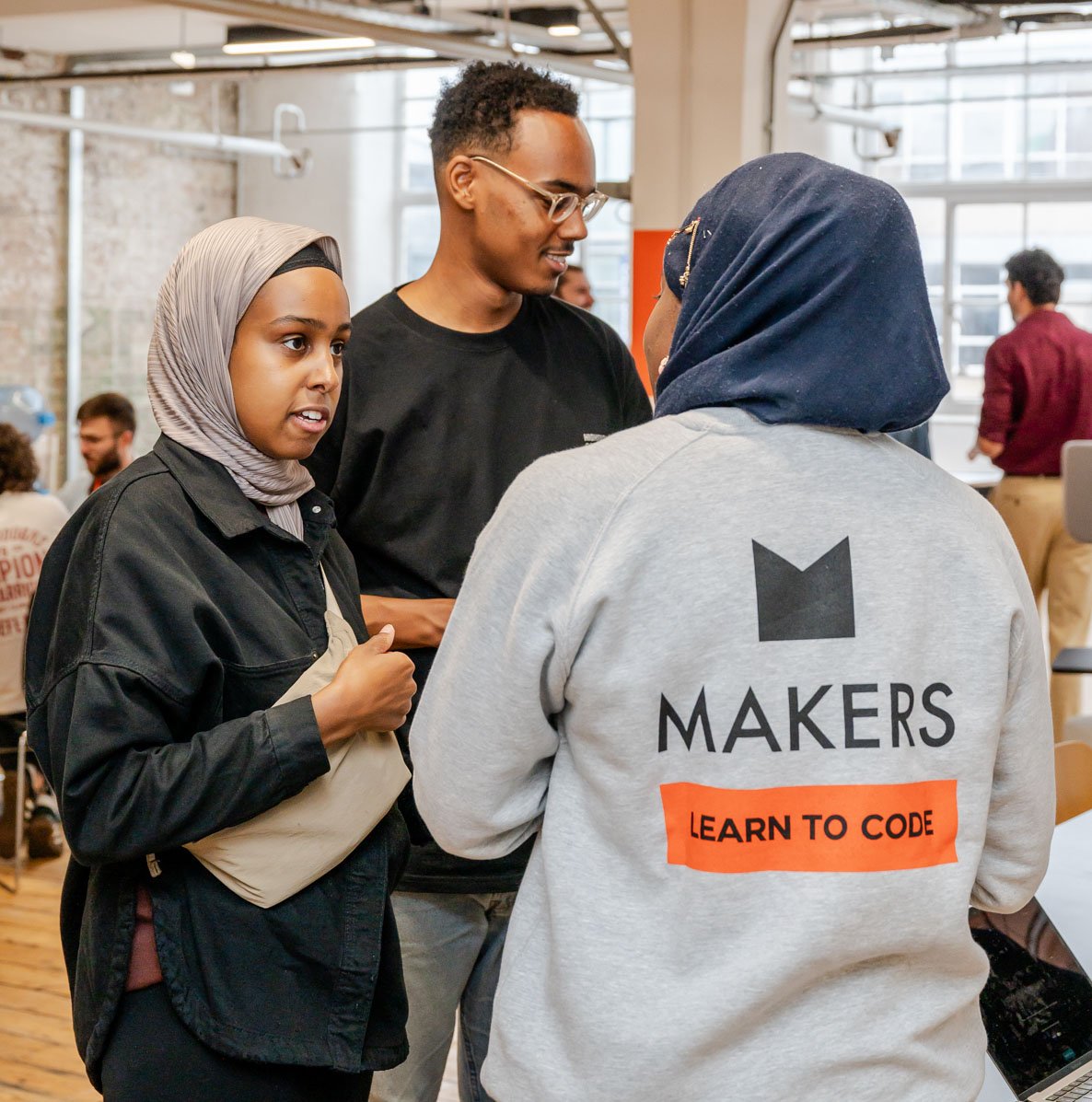 3 Makers talking, one wearing a Makers branded sweatshirt